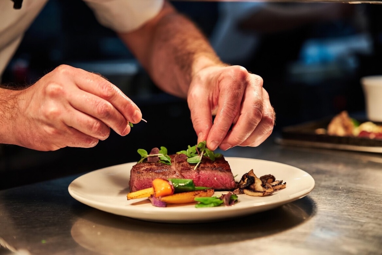 Chef plating a dish featuring locally sourced artisan bread in a Maine restaurant kitchen
